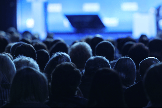 Publikum sitzt vor der Bühne einer Software-Convention 